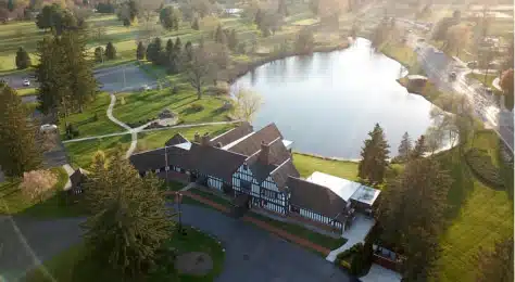 Exterior view of Cascades Manor with lush greenery and a pond.
