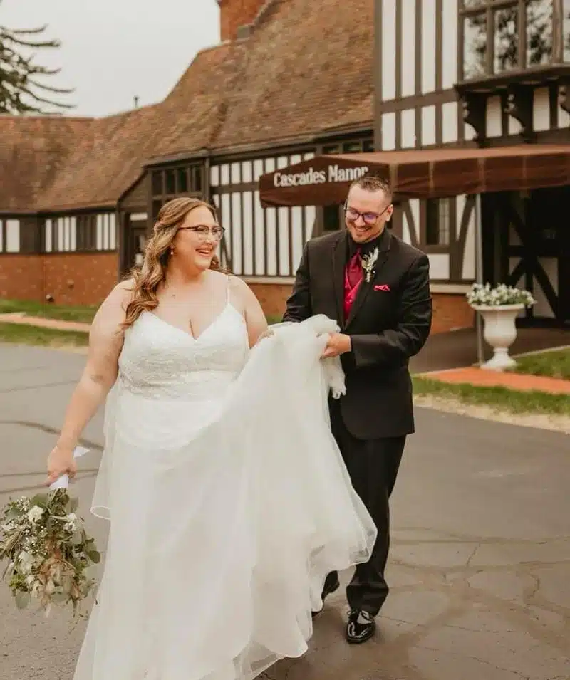 Wedding couple at Cascades Manor, smiling and holding hands outside the venue.
