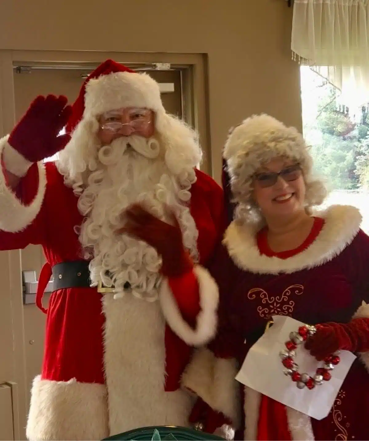 Santa Claus and Mrs. Claus dressed in festive red and white costumes at Cascades Manor holiday celeb.