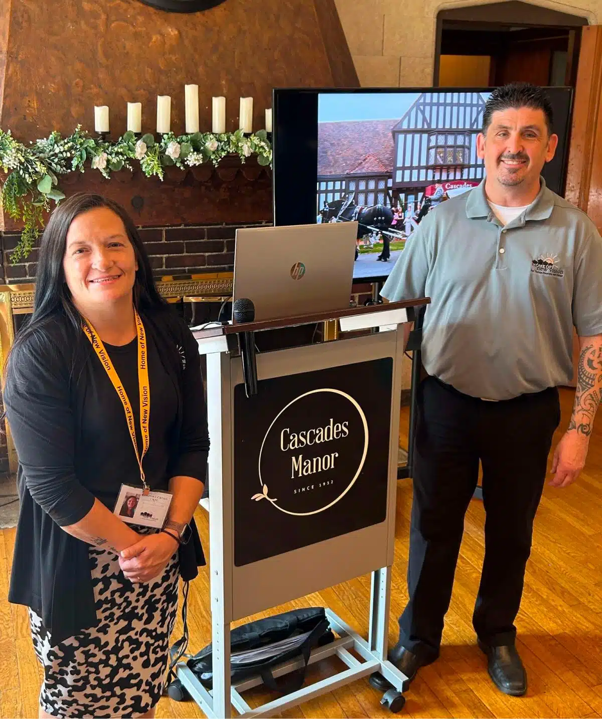 Cascades Manor staff at event registration desk with display screen.