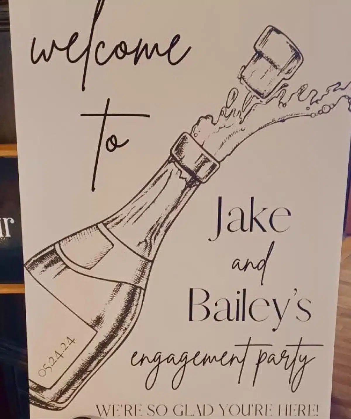 Engagement party welcome sign with champagne illustration.