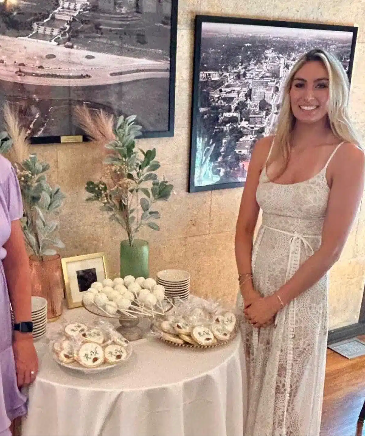 Elegant woman smiling at Cascades Manor with dessert table and cityscape background.
