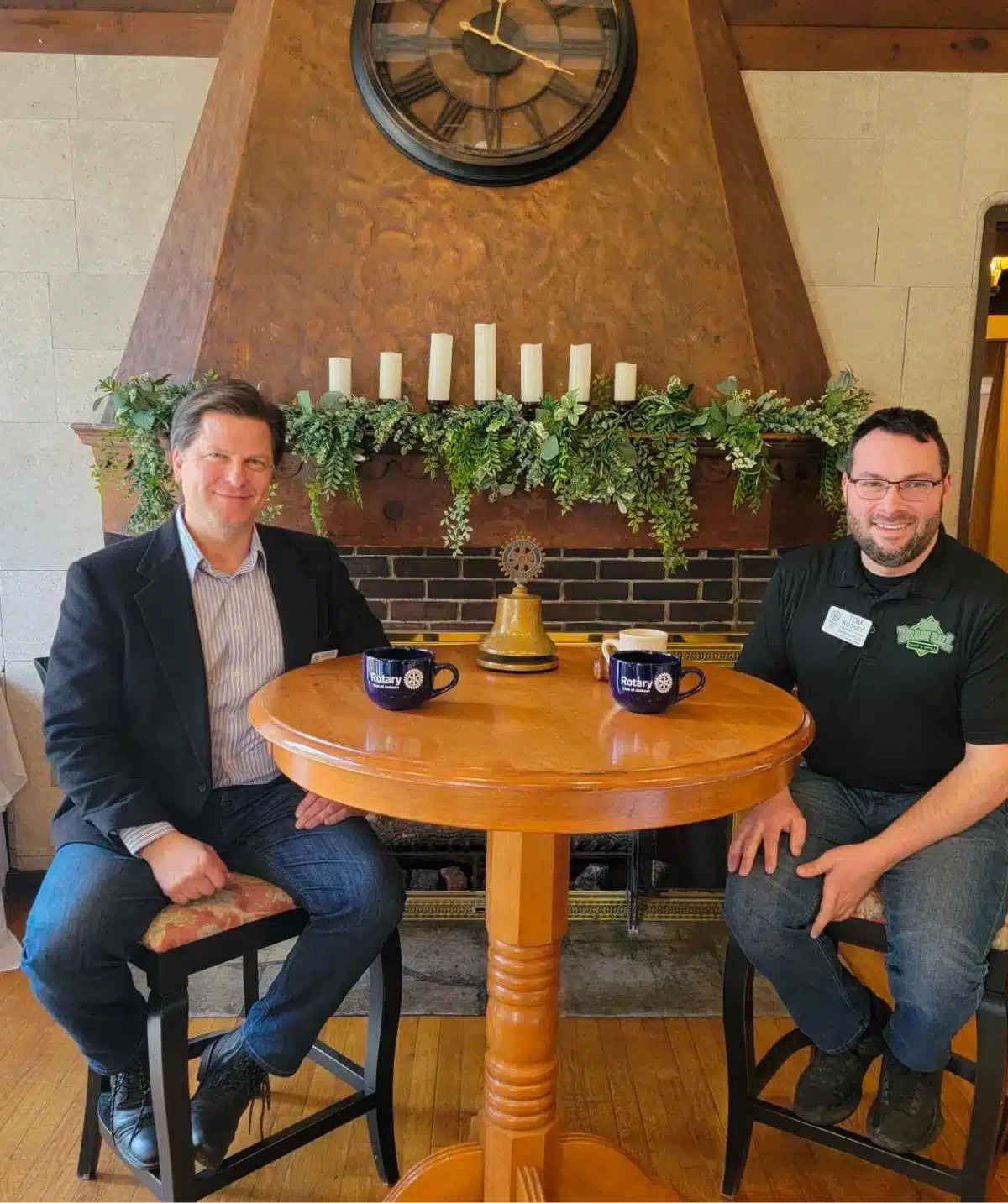 Two men sitting at a round table in Cascades Manor, enjoying coffee.