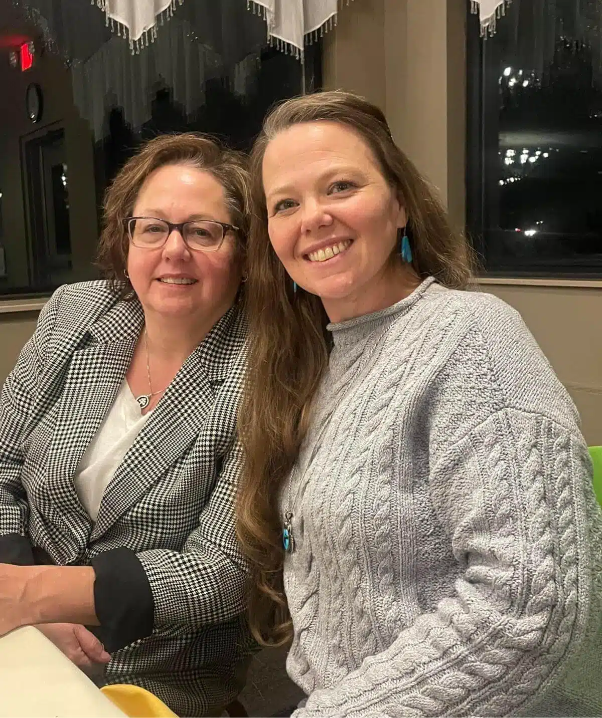 Two women smiling at a dinner event at Cascades Manor.