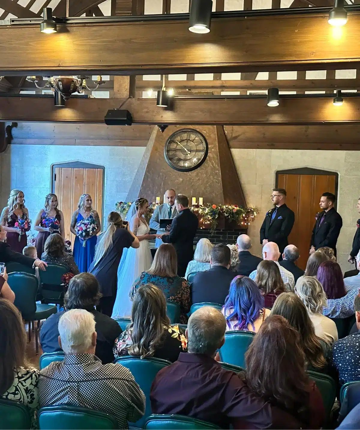 Wedding ceremony at Cascades Manor with bride, groom, and wedding party in a rustic indoor setting.
