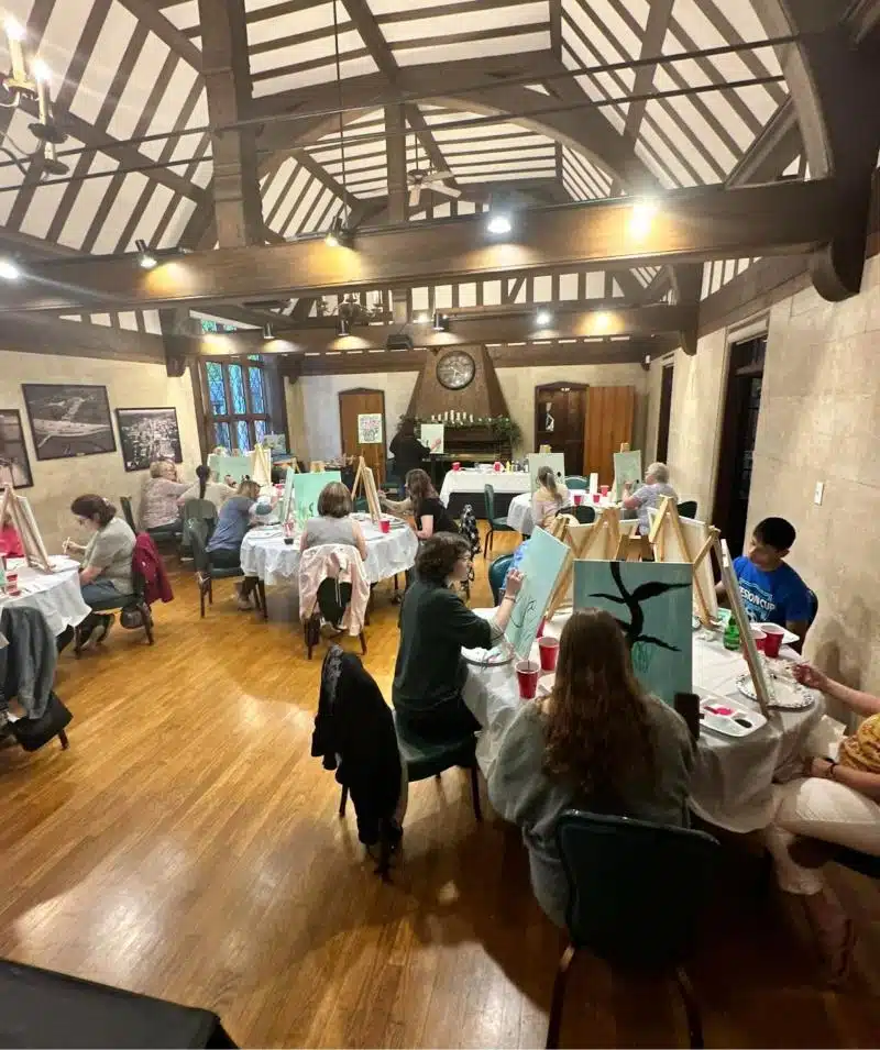 Art class at Cascades Manor with people painting in a spacious, rustic room.