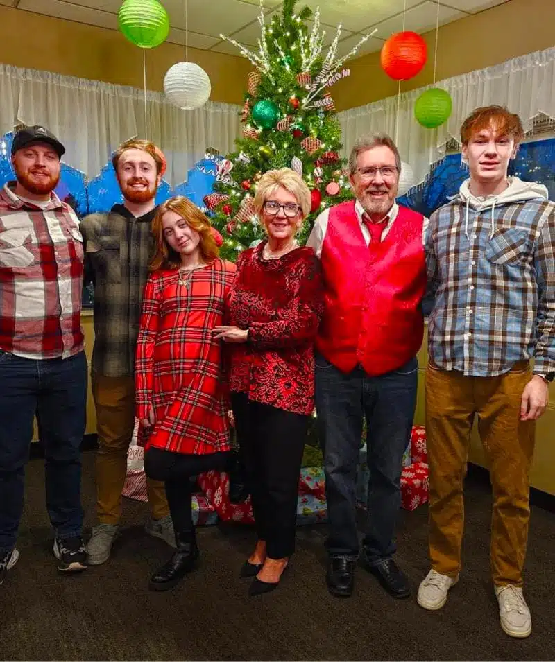 Christmas family gathering at Cascades Manor with decorated tree and joyful smiles.