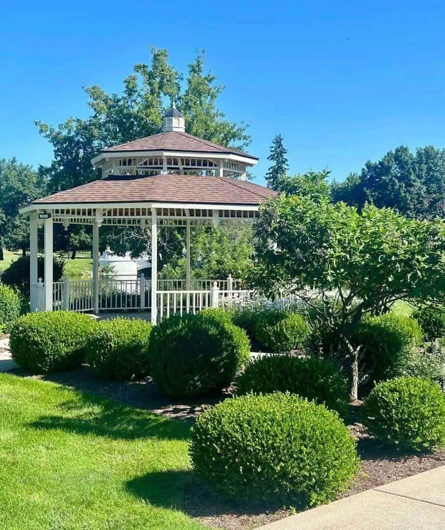 Gazebo at Cascades Manor surrounded by lush greenery and well-manicured bushes.