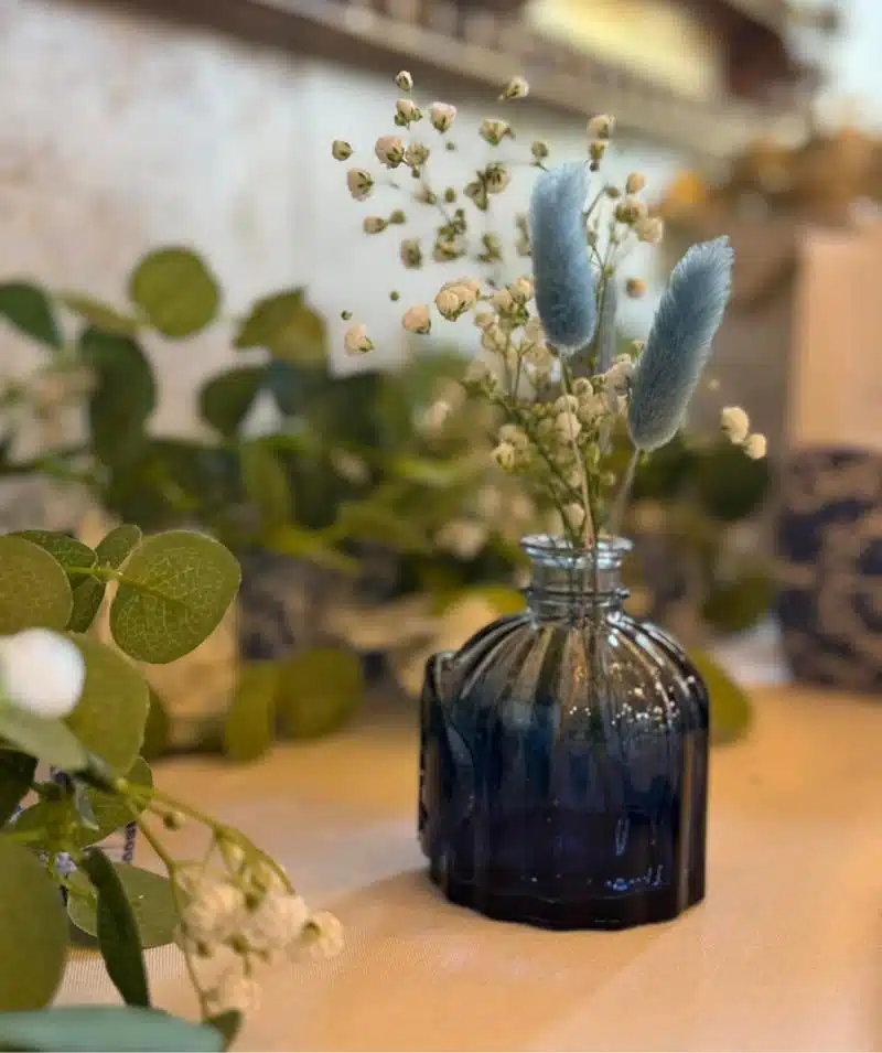 Elegant floral arrangement in a dark blue glass vase at Cascades Manor.