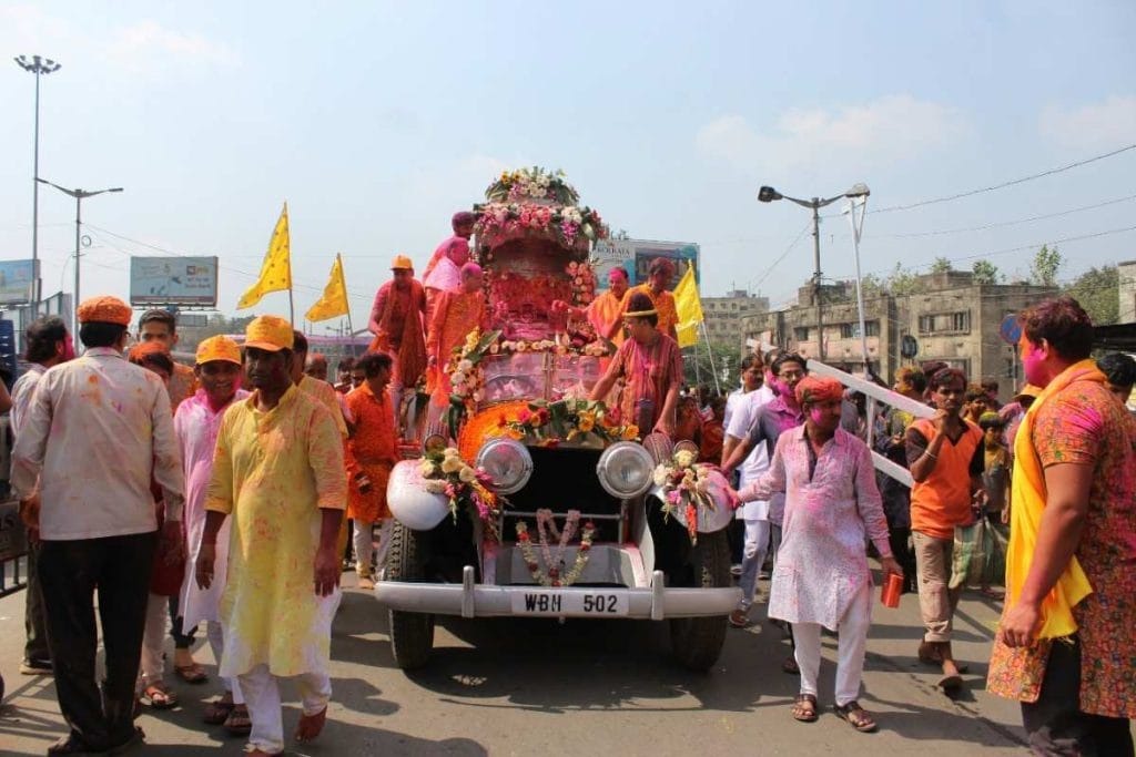 Decorated eight-wheeled chariot being pulled by crowd through Jagdalpur streets