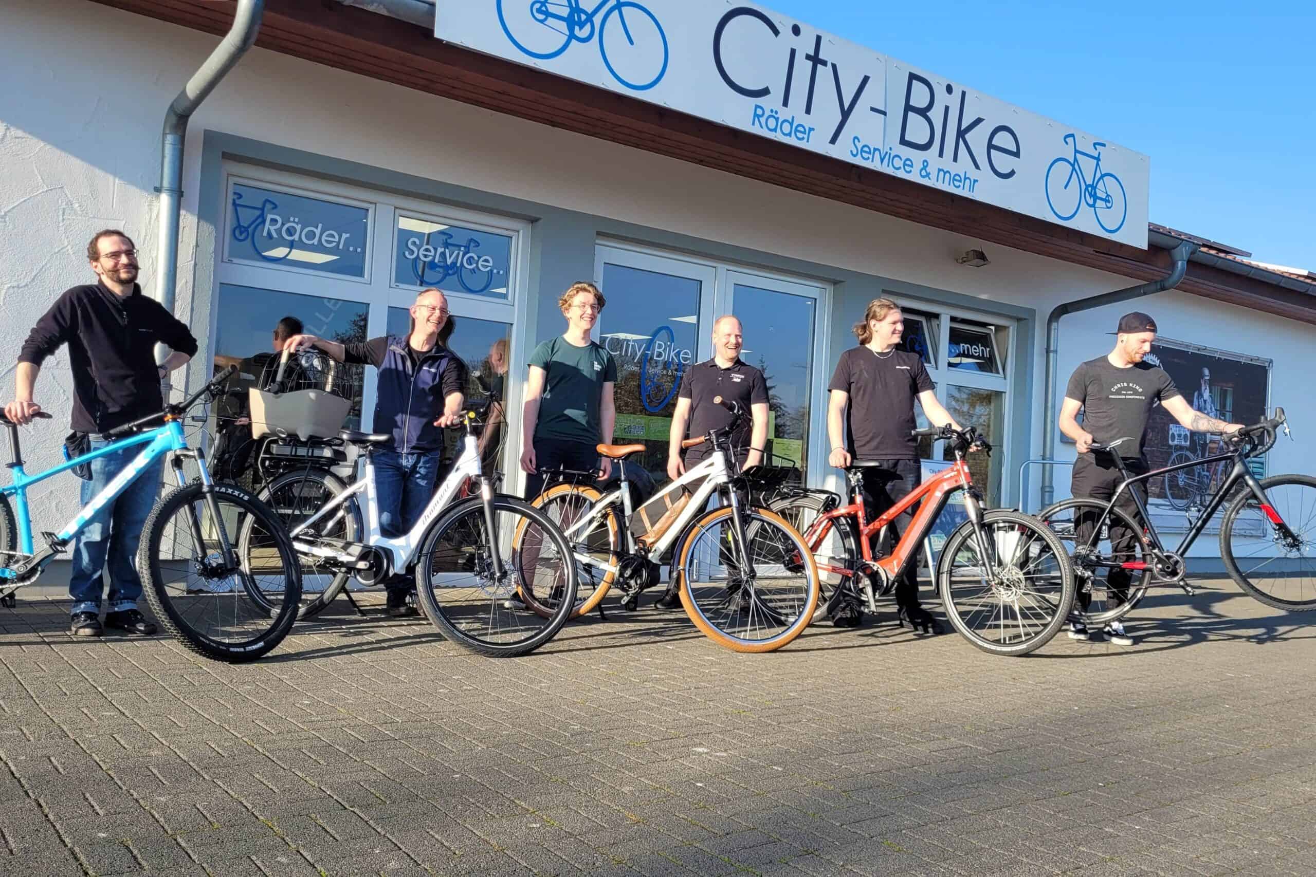 Fahrradverleih bei City-Bike in Einbeck mit mehreren Kunden und Fahrrädern vor dem Laden.