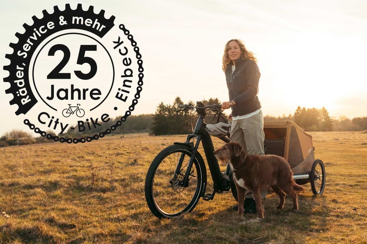 Eine Frau mit Fahrrad mit Hundeanhänger, mit einem Hund in der Natur