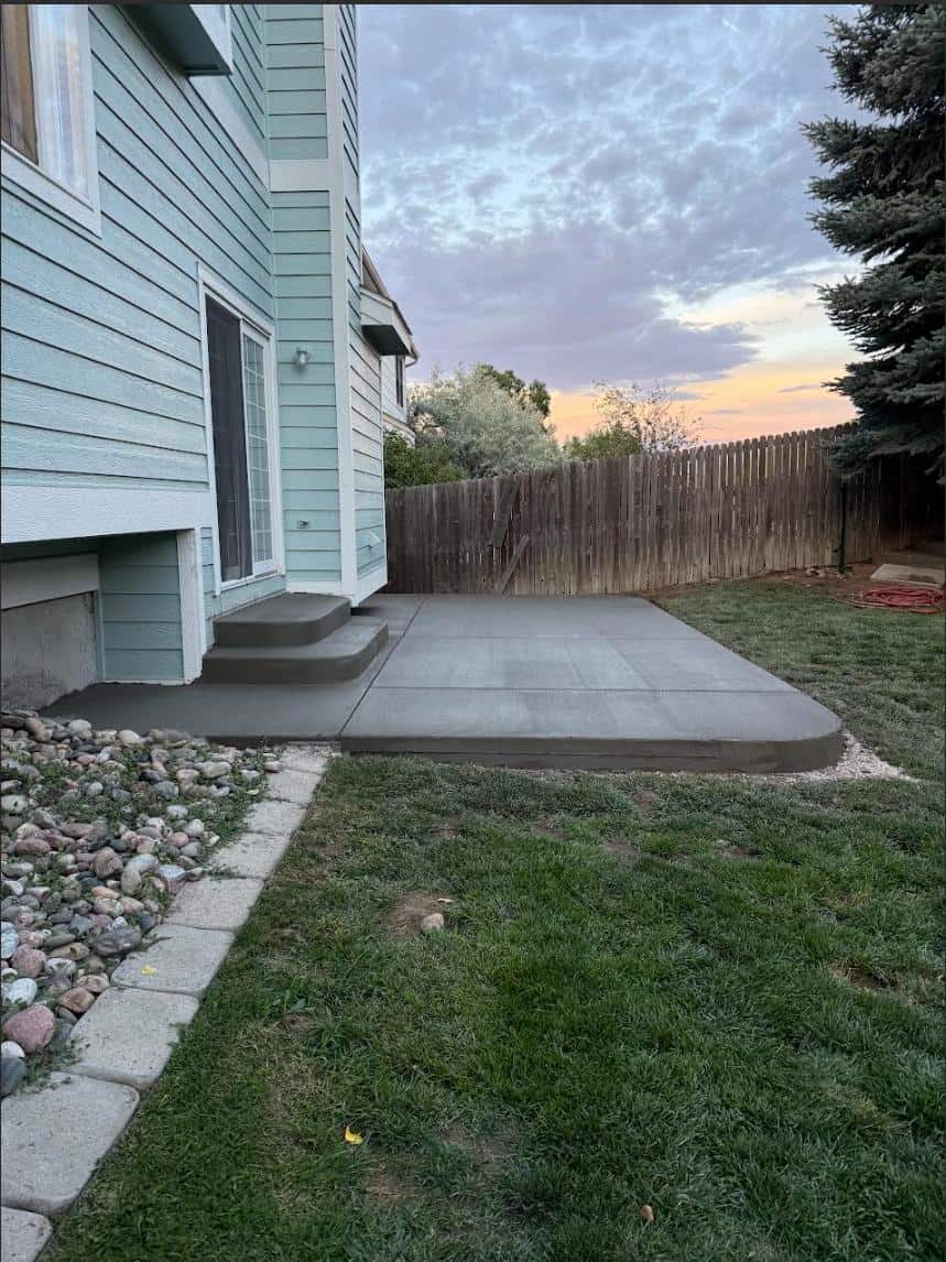 Compact broom-finish concrete patio beside blue siding, captured at sunset in Colorado Springs
