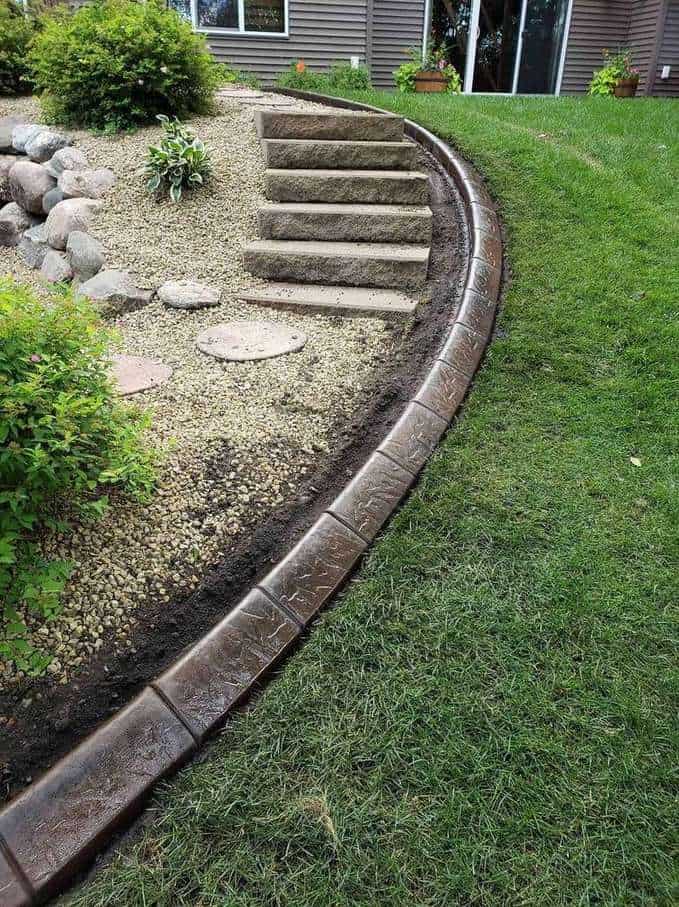 Dark brown stamped concrete edging bordering stone steps and rock garden in Colorado Springs front yard