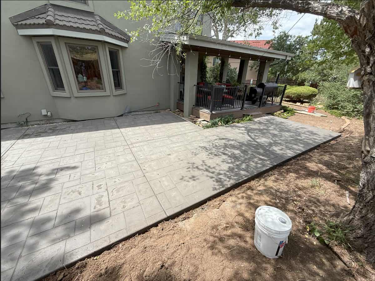 Freshly installed grey stamped concrete patio with ashlar‑slate pattern outside a Colorado Springs home, completed by Co Custom Concrete