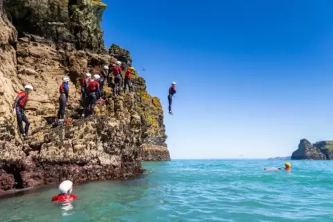 man-jumping-off-rocks-into-sea-768x512