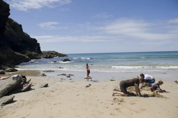 Family on the beach at Poldhu Cove on the Lizard Peninsula, Cornwall.
