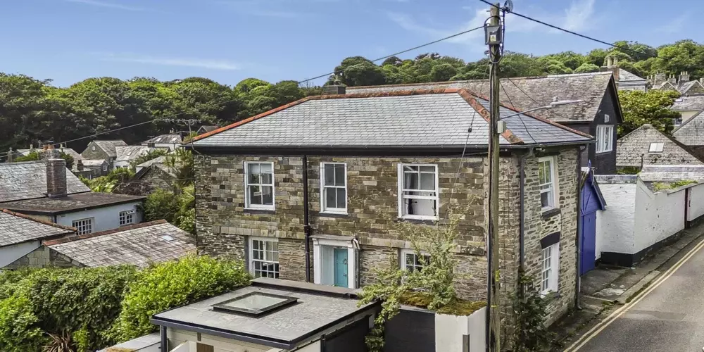 Charming stone built cottage in Cornwall with lush green surroundings and scenic hill views.