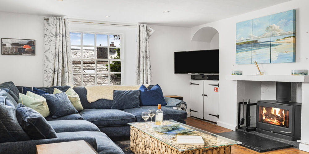 Cozy Cornish cottage living room with fireplace and modern decor, perfect for relaxing holidays.