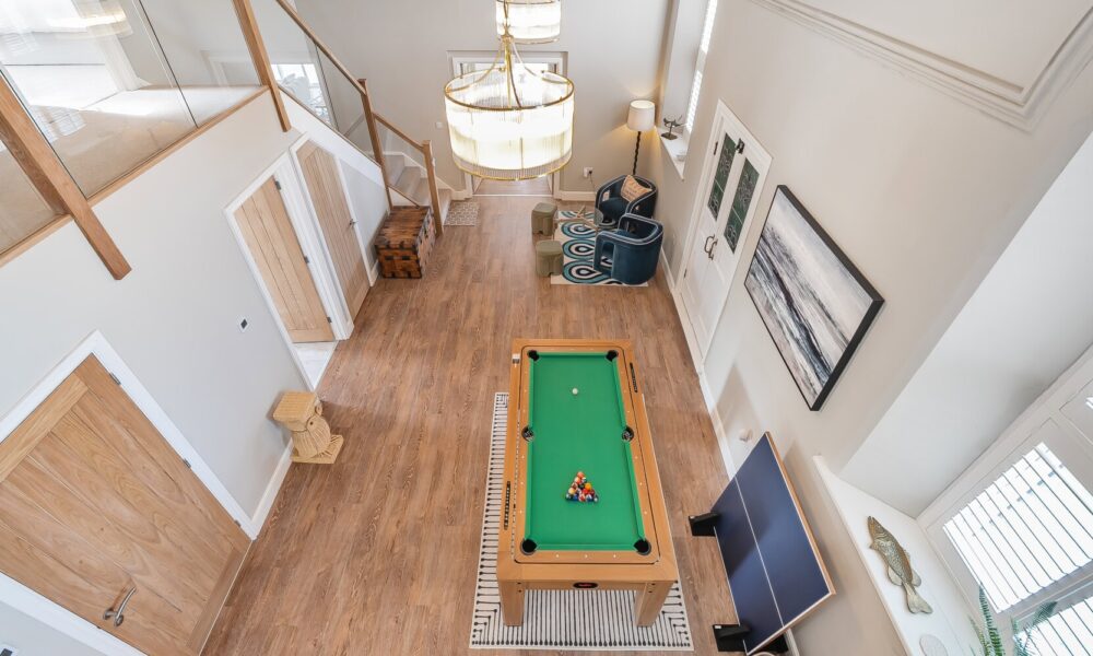 Bright modern living room with pool table, cosy seating area, and stylish decor, perfect for relaxing holiday stays at Cornish Secrets.