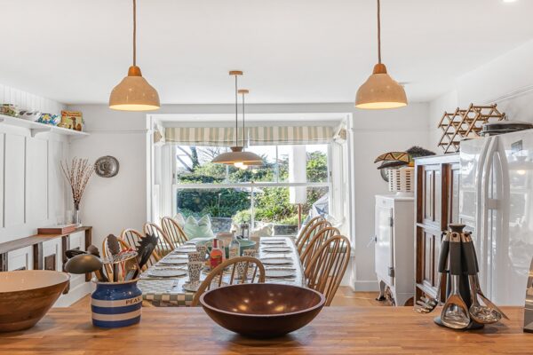 Bright, airy Cornish holiday home kitchen with country-style decor and large dining table.