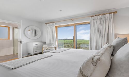 Coastal cottage bedroom with sea view and white decor, relaxing getaway in Cornwall.