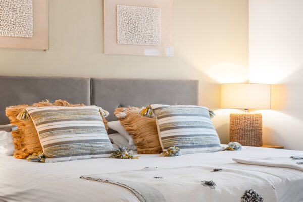 Coastal-inspired bedroom with plush pillows and warm lighting, perfect for a relaxing stay in Cornwall.