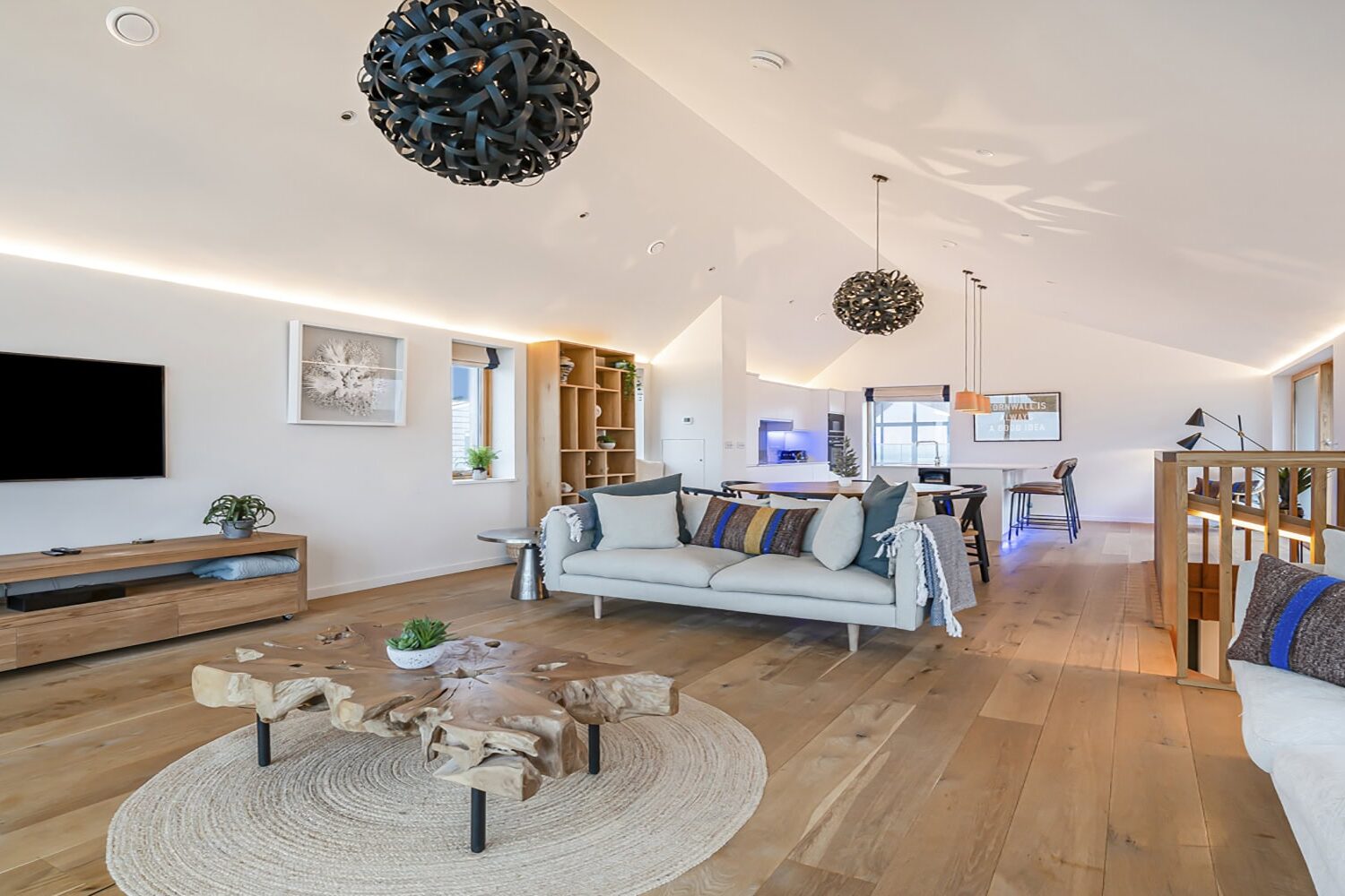 Spacious modern living room with wood flooring, stylish sofas, and contemporary decor.