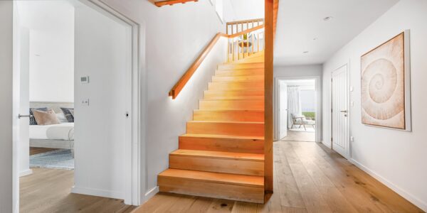 Bright modern hallway with wooden staircase, contemporary decor, and coastal views, perfect for Cornish secrets stay.