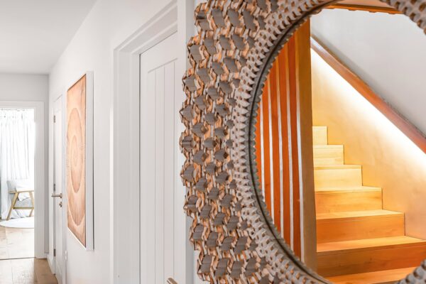 Intricate wooden spiral staircase with warm lighting at Cornish Secrets boutique hotel.