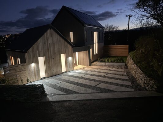 Contemporary wooden house with external lighting and modern landscape design, located in Cornwall.