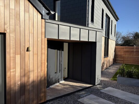 Modern contemporary house exterior with wooden and black cladding, front entry design.