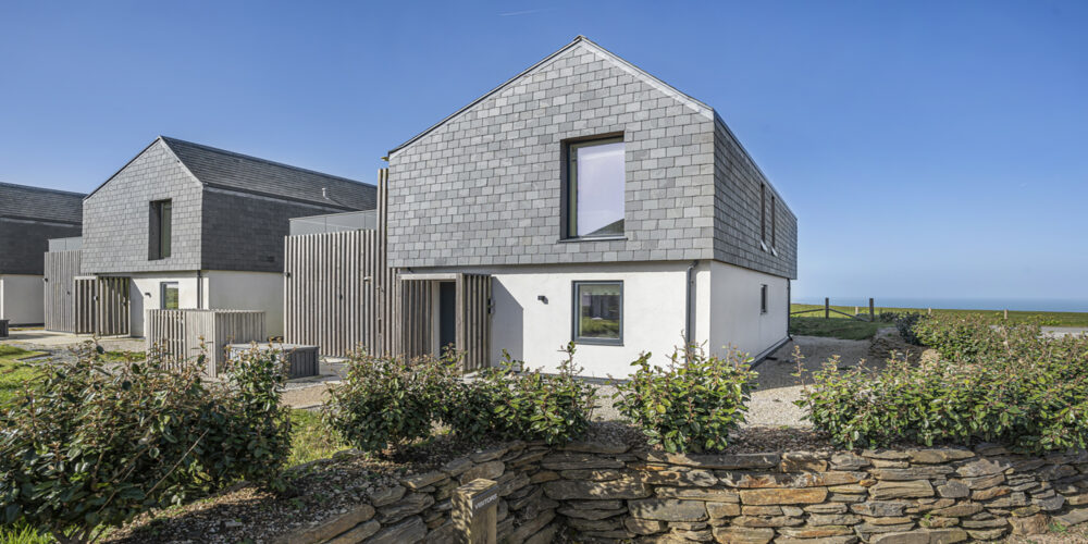 Modern seaside house with grey cladding and large windows.