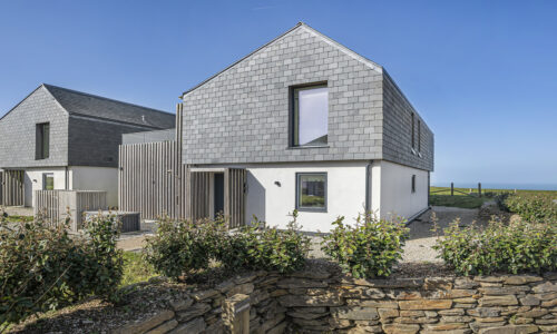 Modern seaside house with grey cladding and large windows.