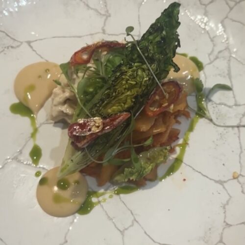 Delicious gourmet dish featuring fresh greens, seafood, and vibrant sauces, showcasing Cornwall's cu.