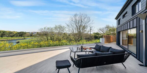 Coastal view from a modern terrace with outdoor seating and scenic countryside in Cornwall.