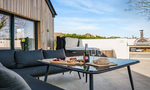 Outdoor dining setup with a table of breakfast items and drinks on a terrace.