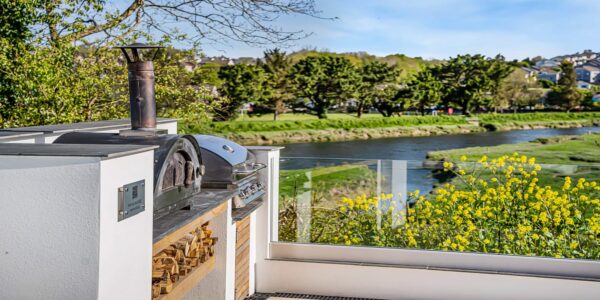 Scenic view of the river with lush greenery and yellow flowers in Cornwall.