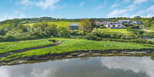 Countryside landscape with lush green fields and a river in Cornwall, showcasing natural beauty and.