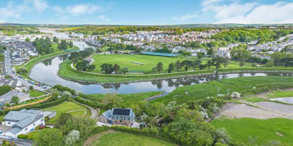 Aerial view of a winding river through lush green landscape near Cornish Secrets, showcasing natural.