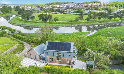 Eco-friendly modern house with solar panels in a lush green landscape.
