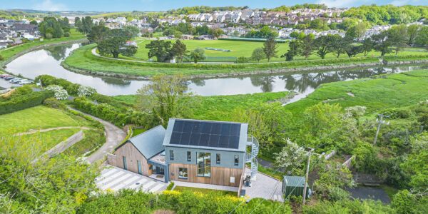 Eco-friendly modern house with solar panels in a lush green landscape.