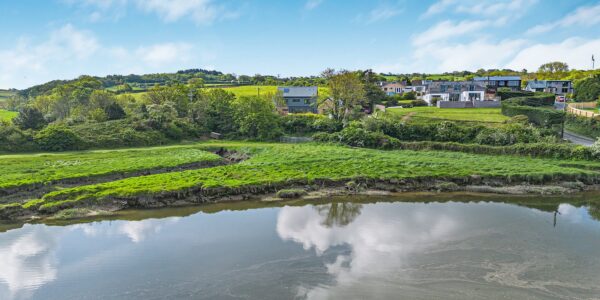 Lakeside scene at Cornish Secrets with lush greenery and calm waters, showcasing the natural beauty.