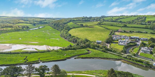 Scenic view of lush green fields, lakes, and rolling hills in Cornwall, showcasing the region's natu.