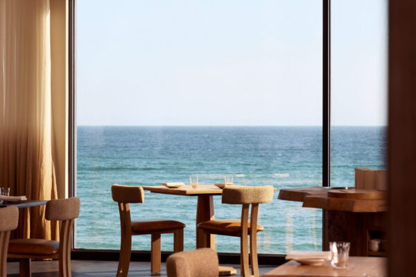 Interior of MOR restaurant with ocean view through large windows.