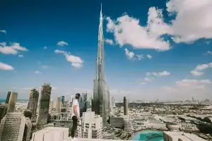 Person looking at Burj Khalifa in Dubai skyline from rooftop.