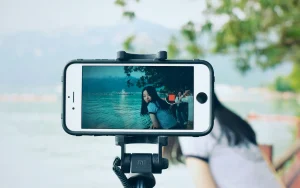 Person taking a photo of a woman by the water for influencer content.
