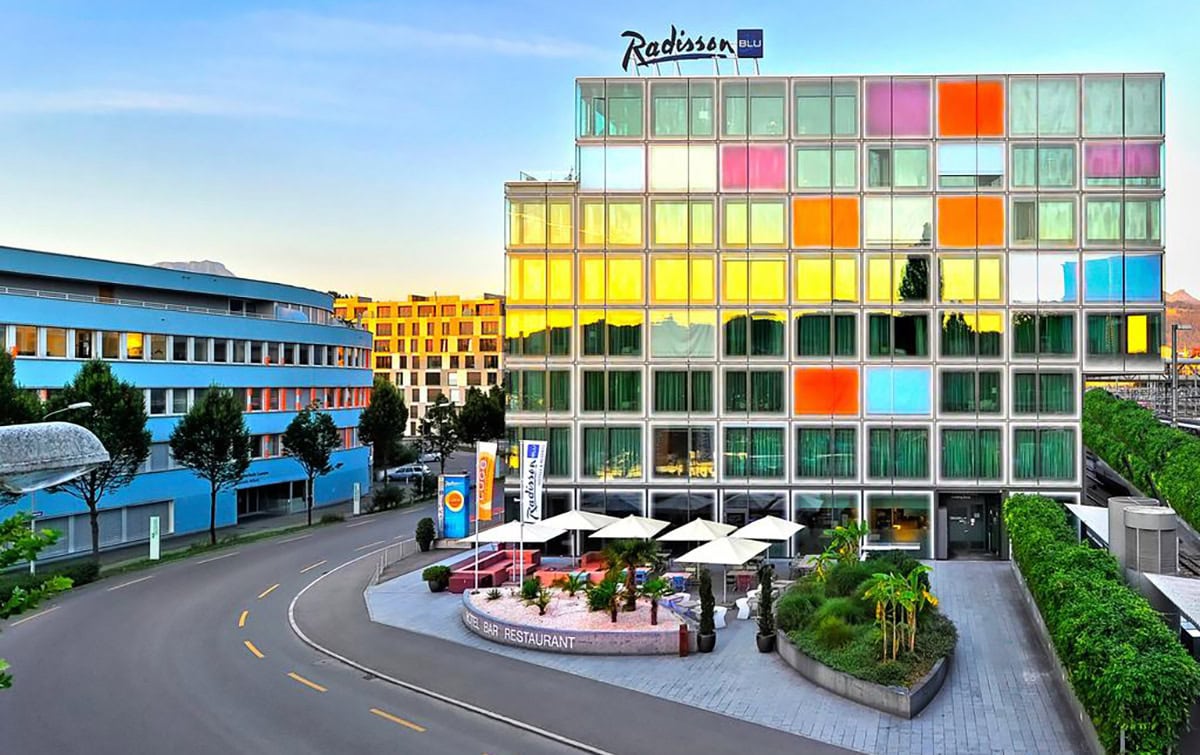 Radisson Blu hotel building with colorful glass facade and outdoor restaurant area.