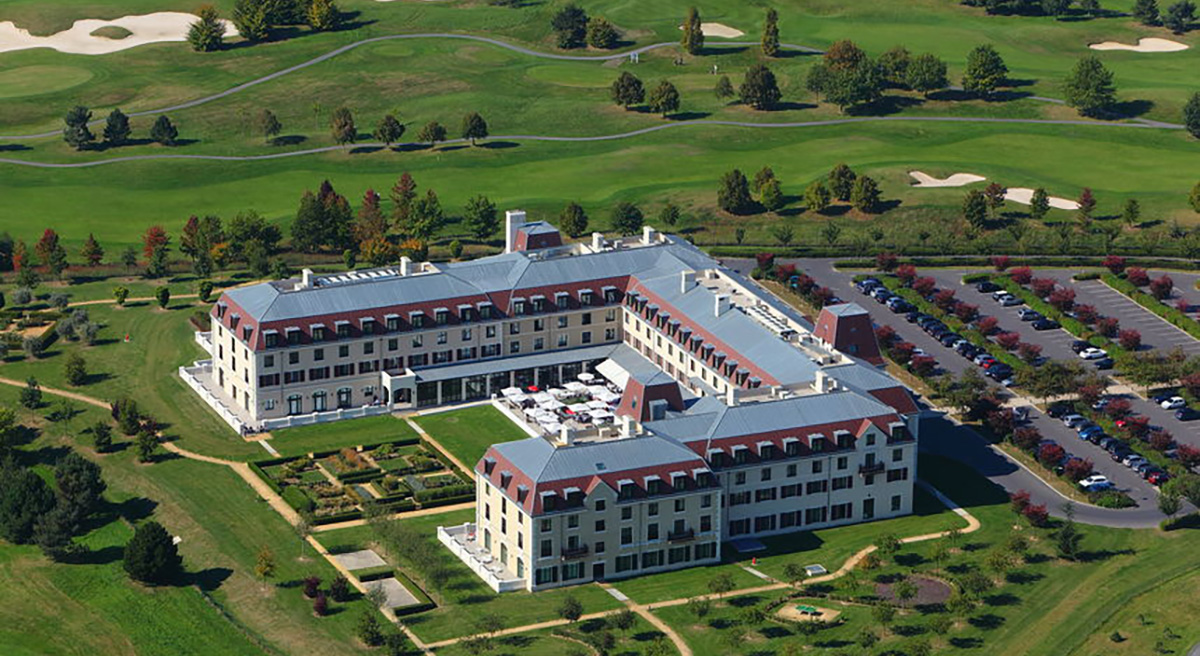 Aerial view of historic hotel and golf course with lush green landscape and manicured lawns.