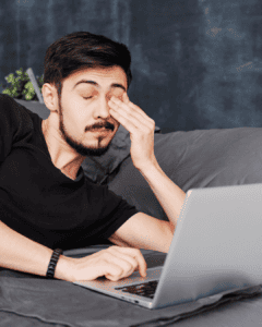 tired man trying to focus at laptop